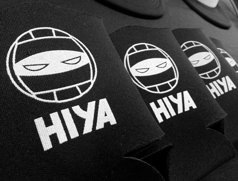 hiya-volleyball-koozies Three black koozies that have icon of volleyball combined with ninja eyes and HIYA text underneath printed on them